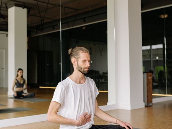 Person sitting cross-legged with eyes closed, practicing breathing.